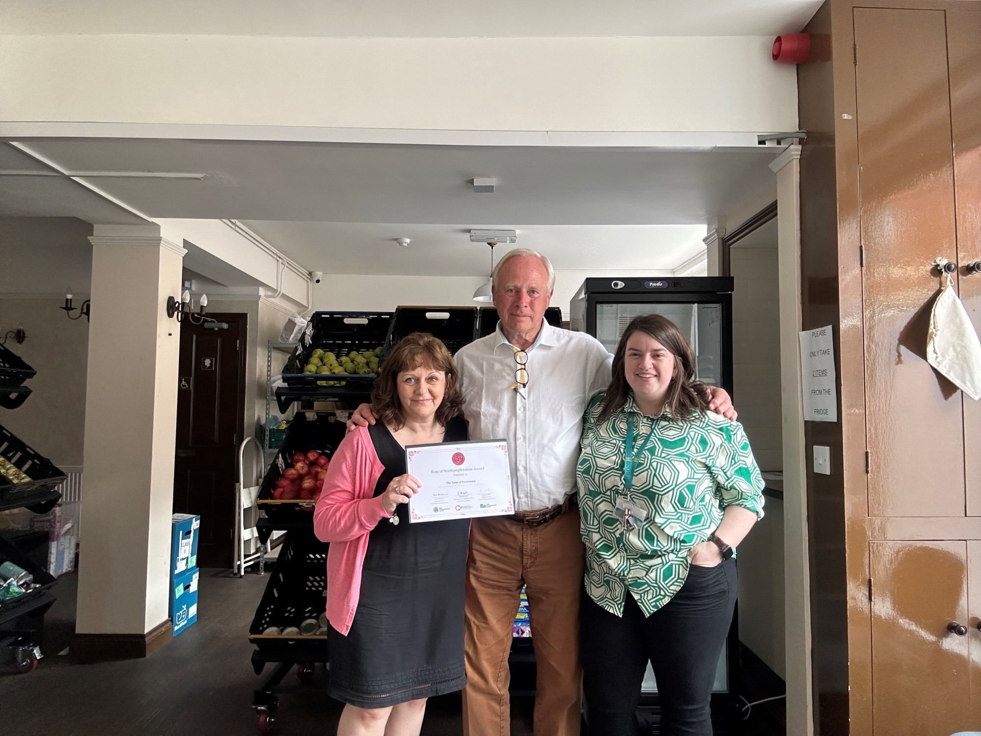 David Laing and two representatives from Encompass charity stand together, David has just presented their Rose of Northamptonshire Award certificate